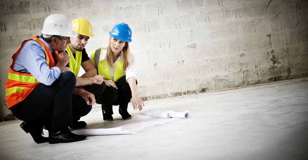 three workers with hard hats working on a plan