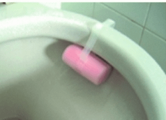 pink toilet rim cleaning block attached to the toilet