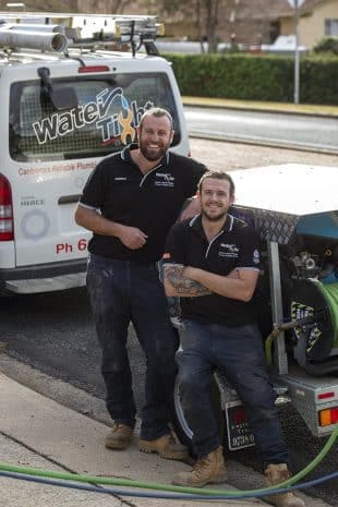 two smiling members of the Water Tight Canberra team with their plumbing equipment
